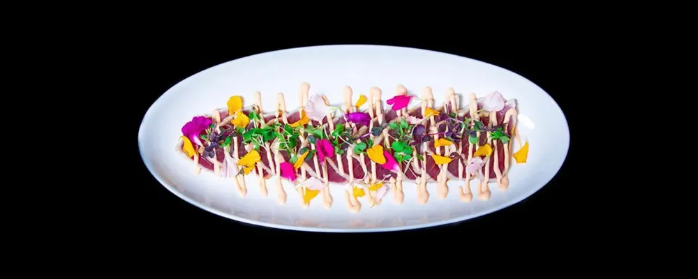 Tuna carpaccio with edible flowers and sriracha aioli